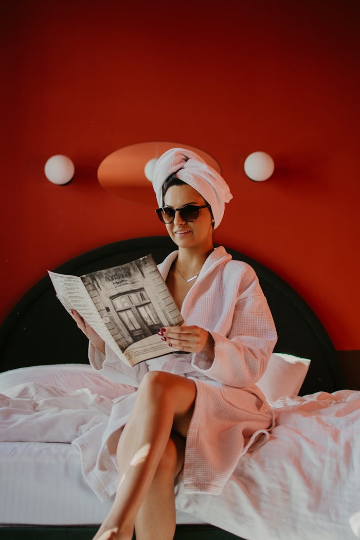 A Woman in a Bathrobe and Head Towel Sitting on a Bed